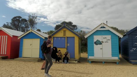 Tourists-walking-and-taking-photo-at-Brighton-Bathing-Boxes,-Melbourne,-Australia