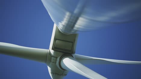 Afternoon-underneath-perspective-and-panning-footage-from-a-wind-turbine-machine-and-its-rotating-blades