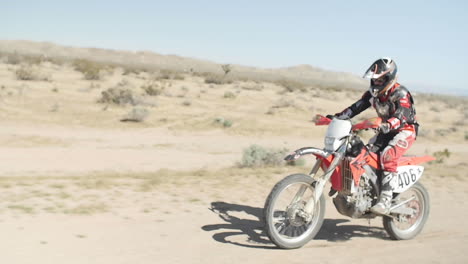 SLOW-MOTION:-A-dirt-biker-rides-his-motorcycle-through-the-desert-from-right-to-left