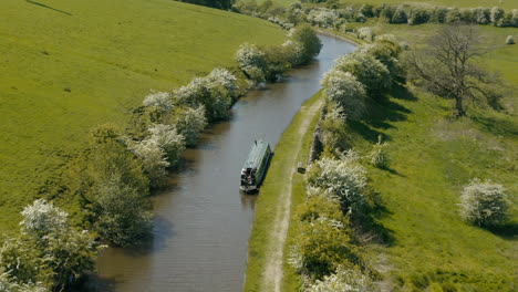 An-aerial-view-of-a-canal-and-canal-boat-surrounded-by-Yorkshire-countryside-on-a-sunny-spring-day