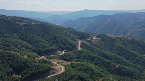 Aerial-view-of-curly-road-in-the-Rhodope-mountains-surrounded-by-green-trees