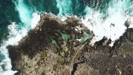 Rising-Drone-Shot-directly-above-waves-crashing-over-the-Makapu'u-Tidepools-off-of-the-Rocky-Coast-of-Oahu,-Hawaii
