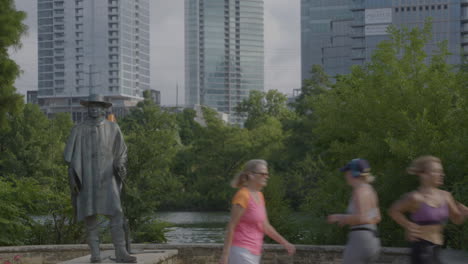 People-running-and-walking-in-front-of-Stevie-Ray-Vaughn-statue-in-Austin,-Texas