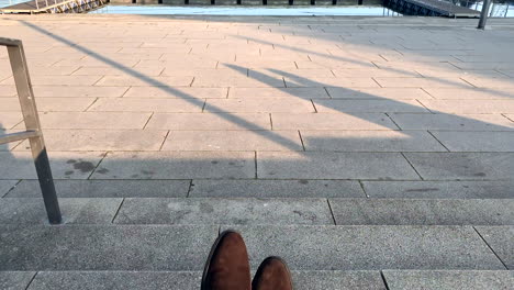 Business-Man-In-A-Brown-Leather-Shoes-is-sitting-on-the-stairs-by-the-lake-after-work-on-sunset