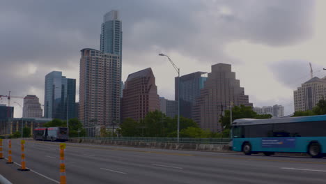 Cars-pass-over-bridge-in-front-of-Austin,-Texas-skyline