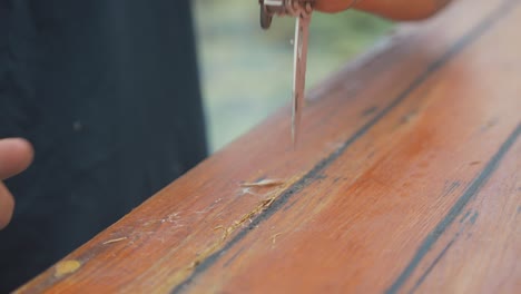 Using-knife-to-cut-damaged-timber-from-wooden-boat-cabin-planking