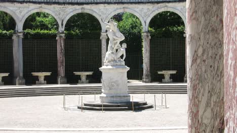 Marble-statue-on-the-center-of-a-small-arena-in-the-Versailles-Palace-gardens,-Paris,-France