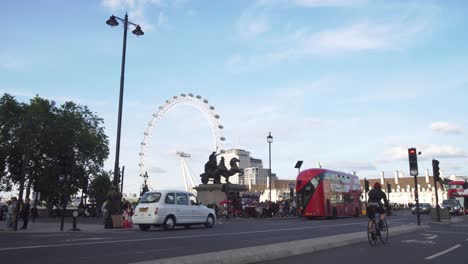 London-Eye-and-people-crossing-street,-cars-and-buses-passing-by