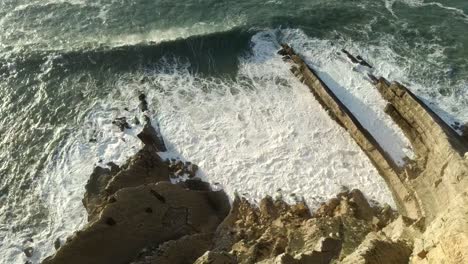aerial-descend-shot-over-the-cliff-and-waves,-sesimbra
