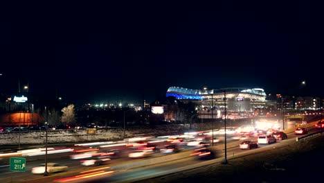 Zeitraffer-Des-Verkehrsflusses-Auf-Der-Interstate-Vor-Dem-Hintergrund-Des-Kilometerhohen-Stadions-Von-Denver-Broncos