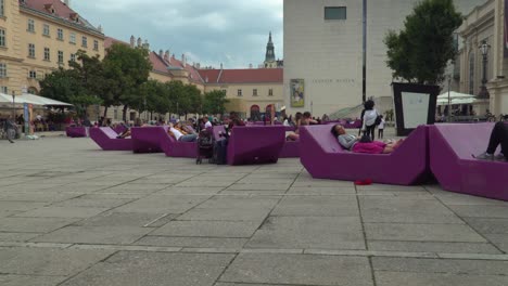 Establishing-ground-level-tilt-up-over-Museumsquartier-in-Vienna,-with-typical-chairs-and-people