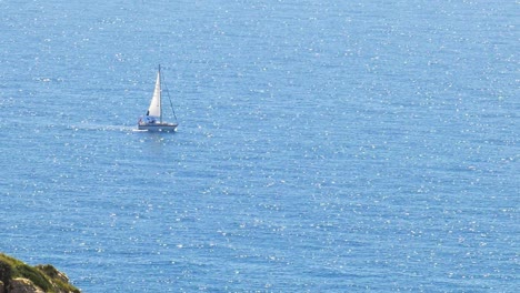 Segelboot-Segelt-Auf-Einem-Glitzernden-Blauen-Meer,-Küste-Spaniens,-Zoom