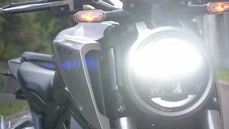 Close-up-of-the-led-lights-of-a-modern-motorcycle-with-the-sunset-in-the-background