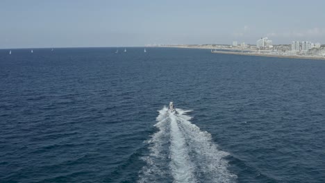 Aerial-tracking-shot-motorboat-sailing-in-Israel-Tel-Aviv-sea,-Drone-shot
