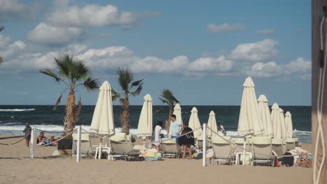 Family-on-the-beach-with-palm-trees,-canopies,-umbrellas-and-sun-beds