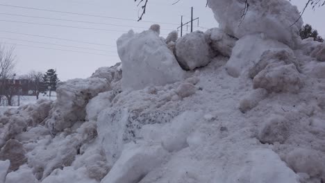 Large-high-snowbanks-at-side-of-road-in-urban-area-in-winter