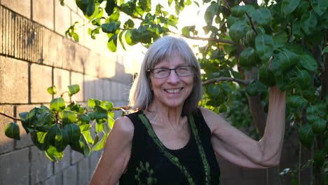 Eine-ältere-Frau-Lächelt-Vor-Freude-Und-Schneidet-Bei-Sonnenuntergang-Zweige-Und-Beschneidet-Einen-Birnenobstbaum-In-Ihrem-Obstgarten