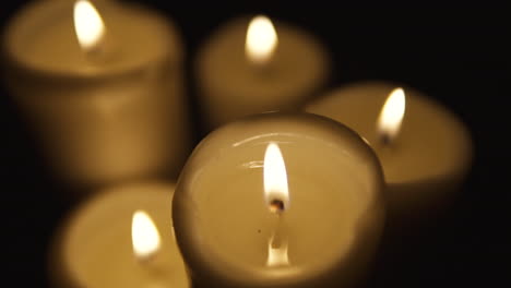 Slide-from-left-to-right,-and-take-focusing-on-burning-candles-occupy-the-whole-area,-composition-on-black-background,-take-focusing-from-blurred,-slow-motion