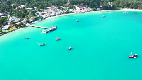 Wunderschöne-Tropische-Türkisfarbene-Lagune-Mit-Festgemachten-Booten-Und-Pier-An-Der-Küste-Mit-Sandstrand