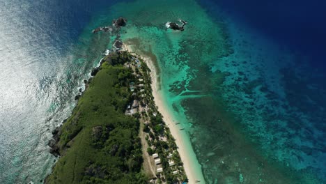 Islas-Fiji---Arrecife-De-Coral-Bajo-El-Agua-Azul-Clara-Del-Océano-Que-Rodea-La-Prístina-Isla-Tropical-En-Fiji-Con-árboles-Verdes-Y-Arena-Blanca---Toma-Aérea