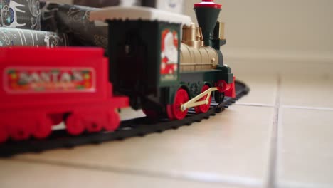 Toy-train-moving-past-Christmas-presents,-slow-motion