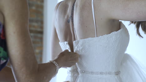 Bridesmaid-zips-up-back-of-bride's-wedding-dress