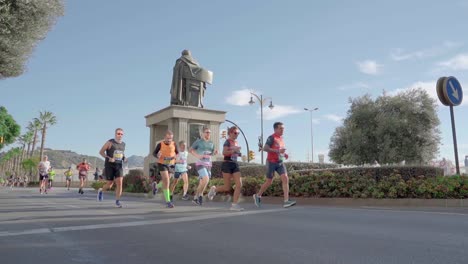 Marathon-runners-run-past-Monumento-Marqués-de-Heredia-in-Malaga,-Spain,-low-angle-shot
