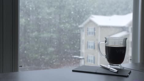 journal-pen-and-coffee-snowing-outside-window-apartments-woodstock-georgia-slow-motion