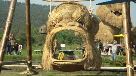 Diversión-En-Un-Columpio-De-Cabeza-King-Kong-En-El-Parque-De-Esculturas-De-Paja-En-Chiang-Mai,-Tailandia,-Rodeado-Por-Un-Hermoso-Paisaje-Y-Exuberantes-Montañas-Verdes