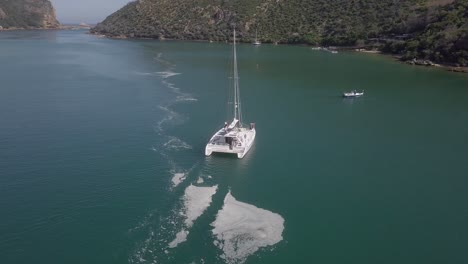 Catamaran-sailboat-motors-slowly-out-of-lagoon-towards-the-open-ocean