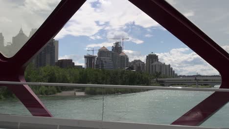 Urban-construction-from-span-of-Calgary-Peace-Bridge,-scooter-goes-by