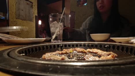 Man-Grilling-And-Serving-Yakiniku-to-Asian-Girl-At-An-Izakaya-In-Japan---close-up