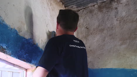 Charity-event-member-paints-with-brush-inside-walls-of-classroom-during-a-charity-event-in-Ziway,-Ethiopia