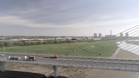 Vehicles-crossing-contemporary-Mersey-Gateway-bridge-aerial-view-at-low-tide-pan-right