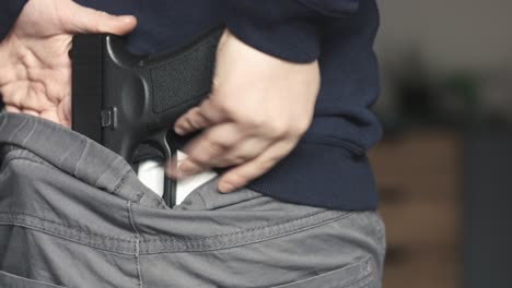 Close-up-of-a-young-boy-placing-a-nine-millimeter-toy-gun-perfect-replica-on-the-back-of-his-pants-and-then-hiding-it-under-his-sweatshirt