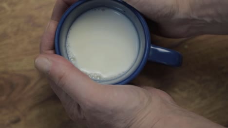 Hand-holding-mug-of-milk-flat-lay-close-up