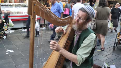 Old-Jewish-man-plays-harp,-sings-on-busy-Jerusalem-market,-street-performance