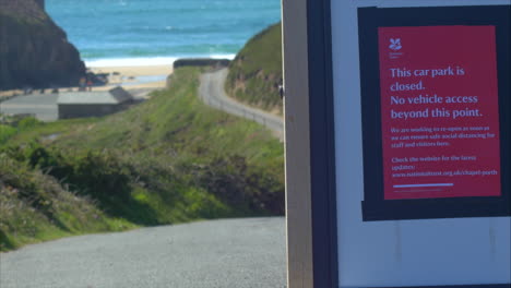 Closed-car-park-sign-at-beach-with-sea-in-background,-close-up