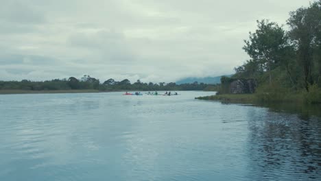 Group-of-kayakers-out-paddling-on-river,-Wide-tracking-shot