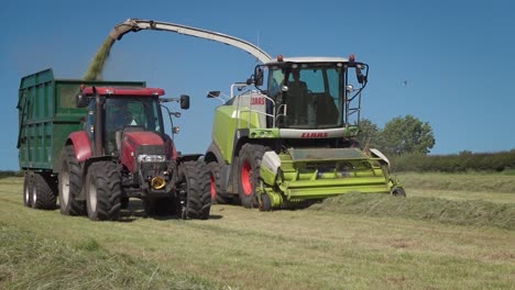 Agricultural-Contractors-running-large-machines-to-pick-up-rows-of-cut-grass-for-silage-winter-feed