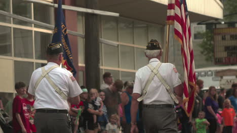 Miembros-De-La-Legión-Americana-Caminando-Con-Banderas-En-Desfile-Por-Calles-Llenas-De-Gente-En-Pensilvania,-Cámara-Lenta