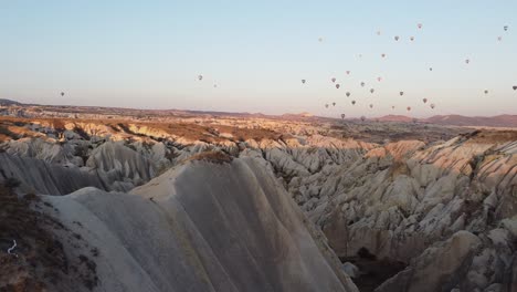 Brunnette-girl-whatching-the-sunrise-in-Cappadocia-under-a-sky-of-colorful-balloons