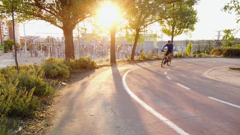 A-cyclist-riding-on-a-bike-lane-in-the-sunrise-near-a-electricity-transformer-station