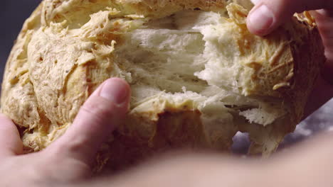 Hands-Breaking-Apart-Fresh-Baked-Bread,-Close-Up