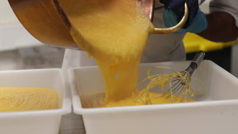 Pouring-Hot-Custard-Cream-Into-Plastic-Baking-Pans---close-up,-panning-right-shot