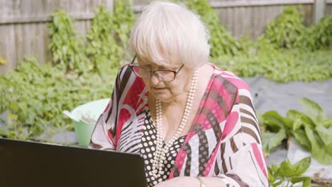 Ältere-Frau-Arbeitet-Draußen-Im-Garten-An-Einem-Schwarzen-Laptop