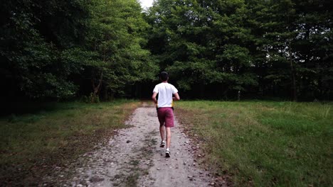 Young-Caucasian-male-running-in-forest-on-a-trail-in-summer