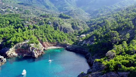 Cala-Deia-cove-in-Mallorca-Spain-with-white-yachts-anchored,-Aerial-dolly-out-shot