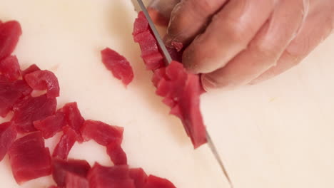 Chef-Cutting-Tuna-Meat-In-Small-Pieces-Using-Knife-On-Chopping-Board