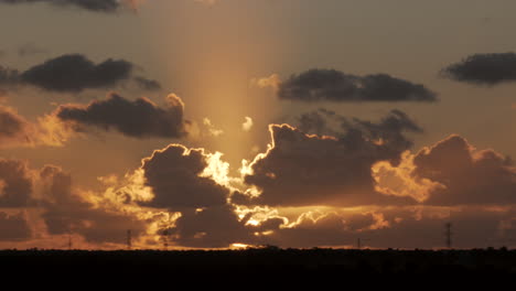 Statische-Weitwinkelaufnahme-Gigantischer-Goldener-Sonnenuntergangslichter,-Die-Hinter-Der-Bewegten-Wolkensilhouette-Am-Horizont-Leuchten